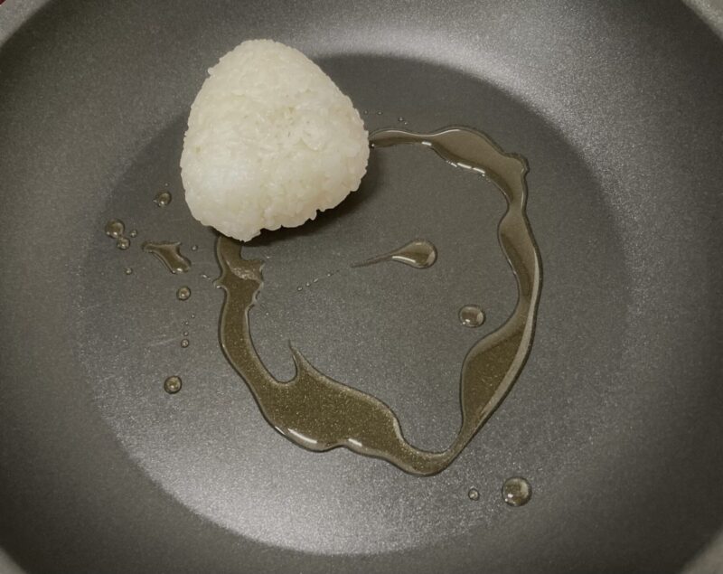 フライパンにごま油とおにぎりを置いている